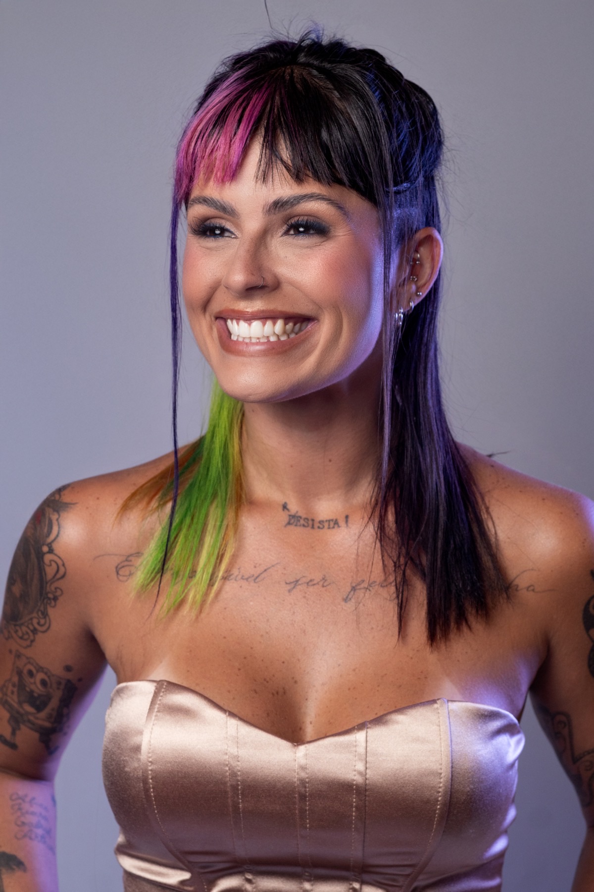 Rafa Guttierrez sorrindo em retrato de estúdio, cabelo com mechas coloridas